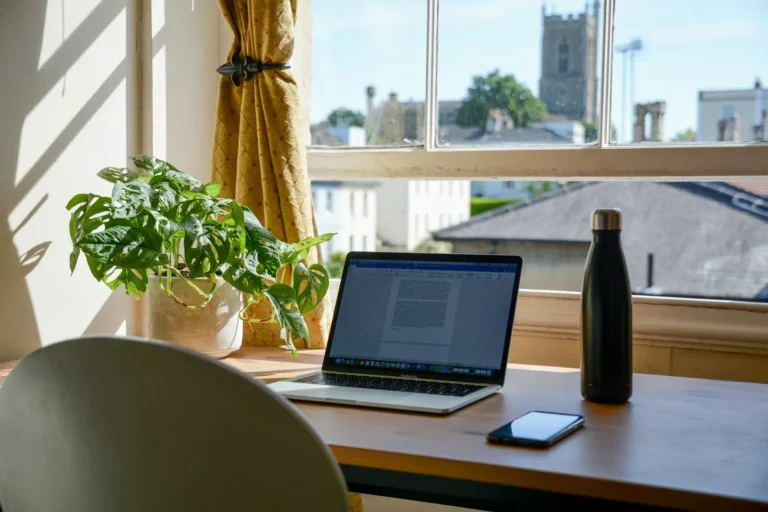 Home office pequeno com notebook em mesa de madeira perto da janela