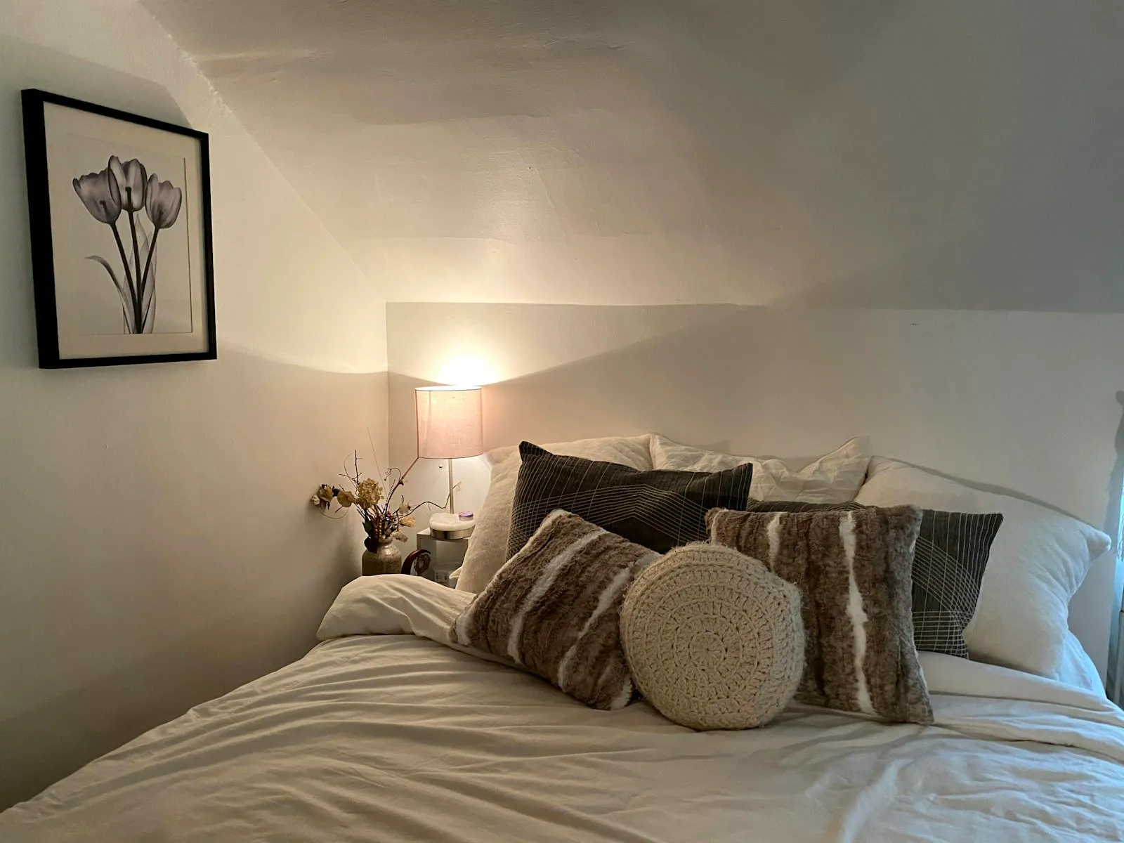 Quarto de casal aconchegante com cama, almofadas e luz quente