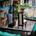 Varanda pequena com cadeira, vasos de plantas e guarda-corpo